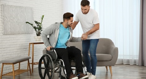 Man standing and helping a man in a wheelchair
